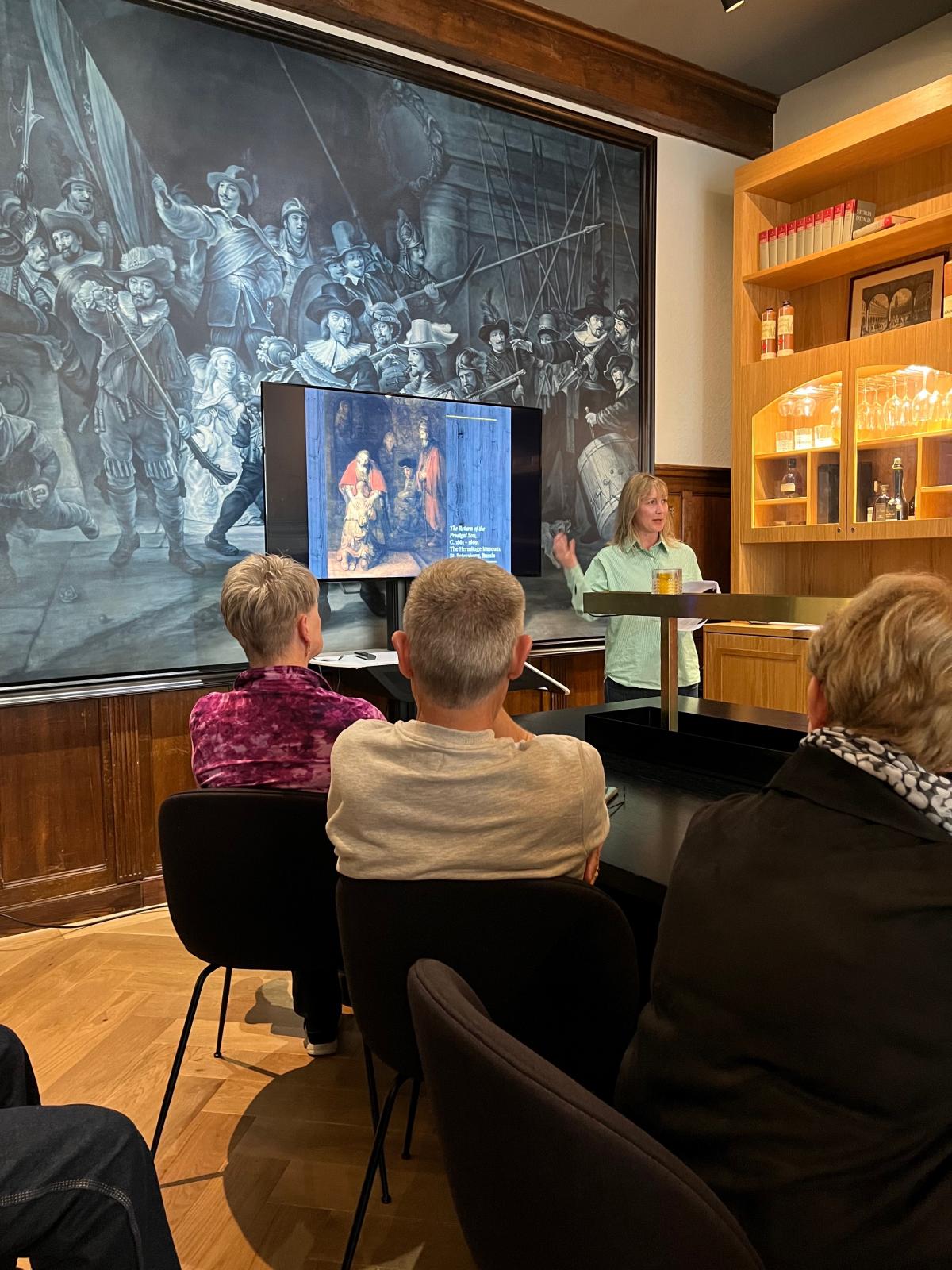 People sitting down watching a person speak at a podium