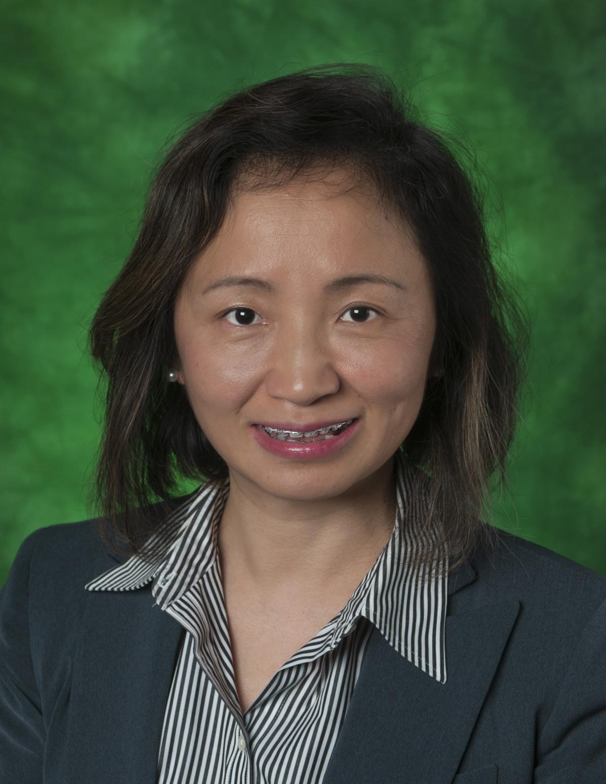 Yan Huang in front of green background