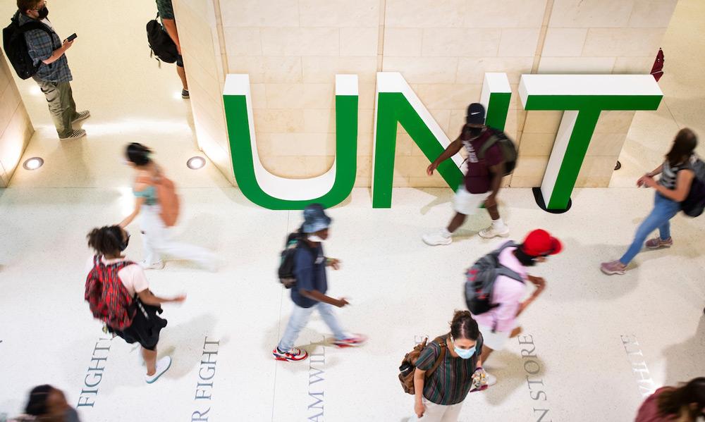Students walking through the Union in front of large "UNT" letters