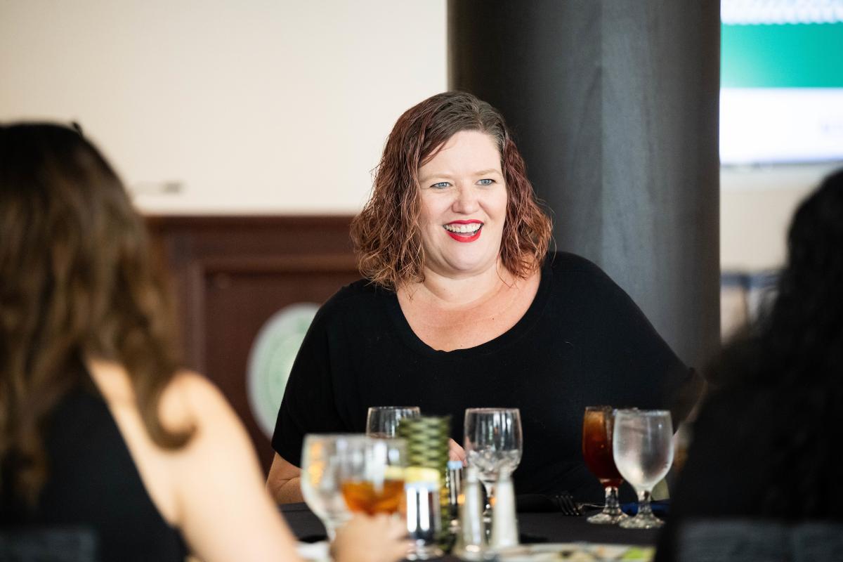 Faculty member smiling at a table with colleagues