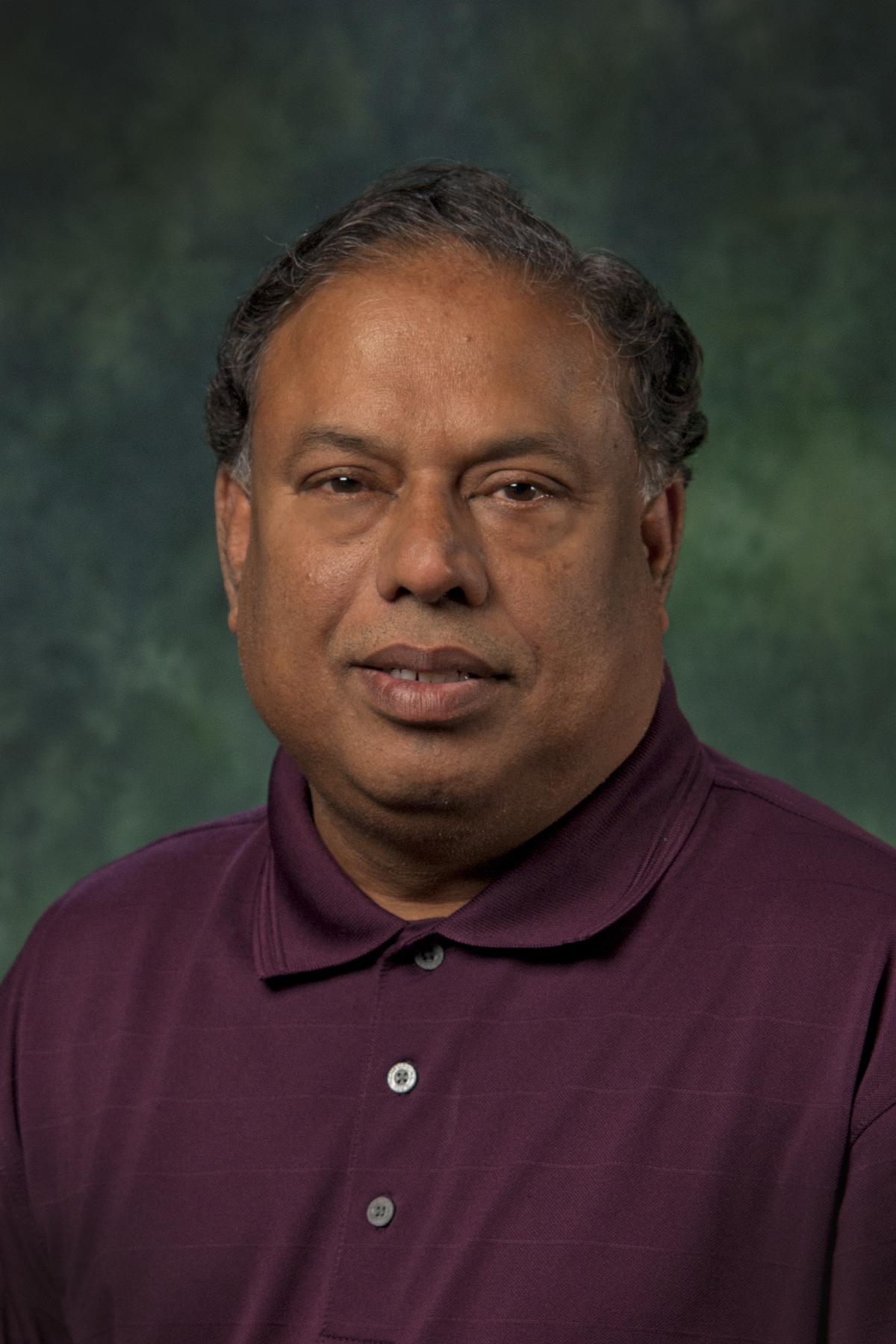 Pudur Jagaseeswaran in front of a green background