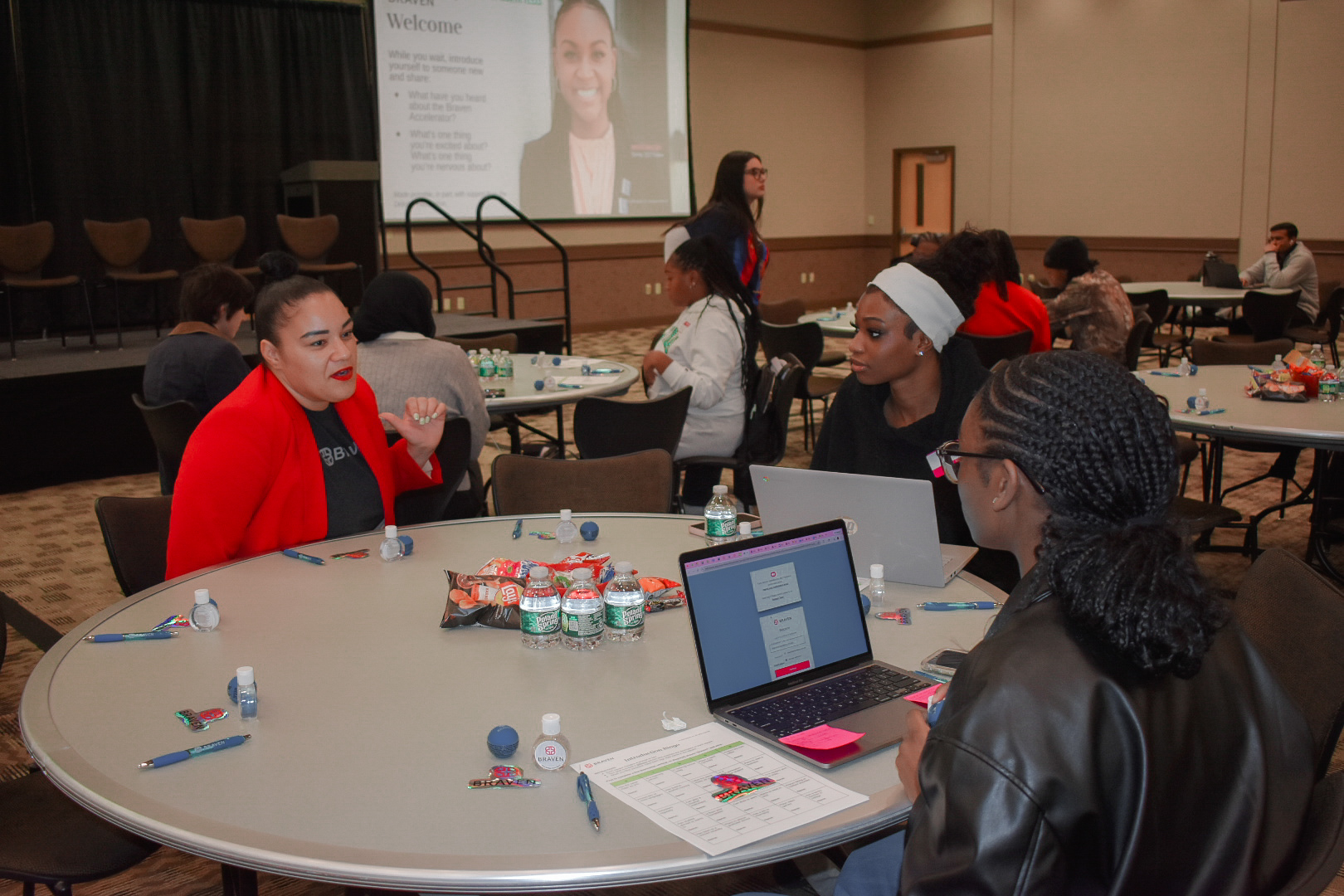 Three women with laptops sitting at a table talking