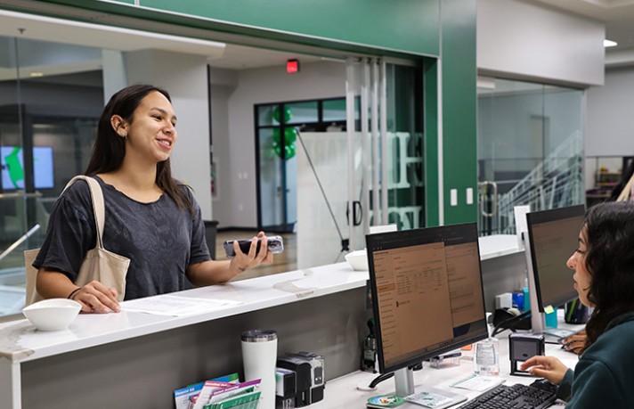 a student talking to a staff member at the front desk of the UNT one stop